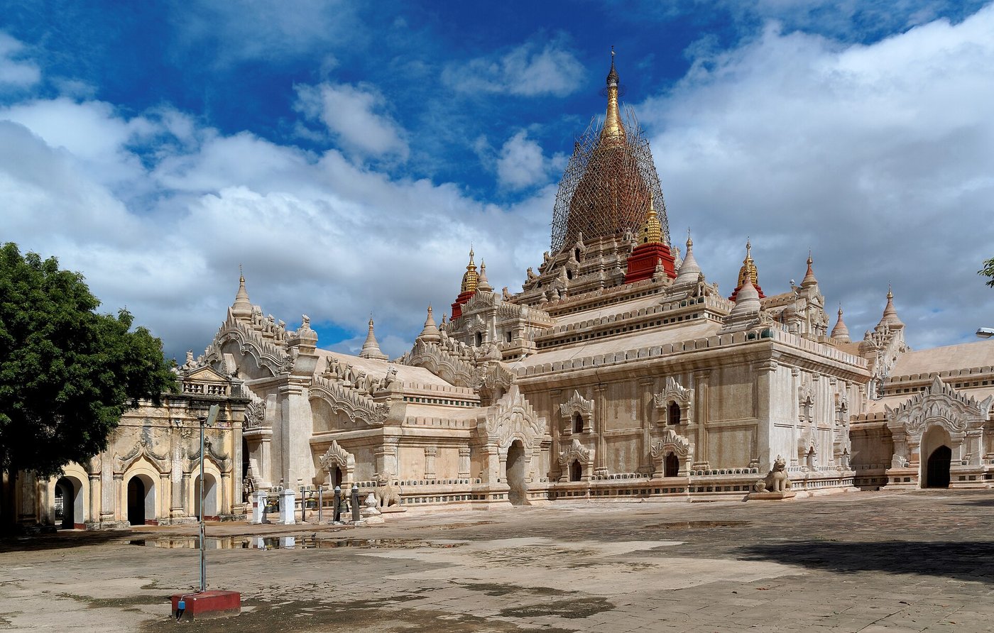 The Ananda Temple at Bagan, a whitewashed temple with terraced roofs rising to a tall golden spire against a blue sky