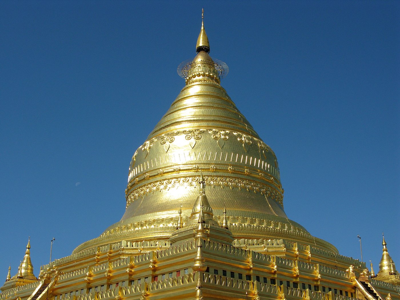The golden bell-shaped stupa of the Shwezigon Pagoda gleaming against a clear blue sky