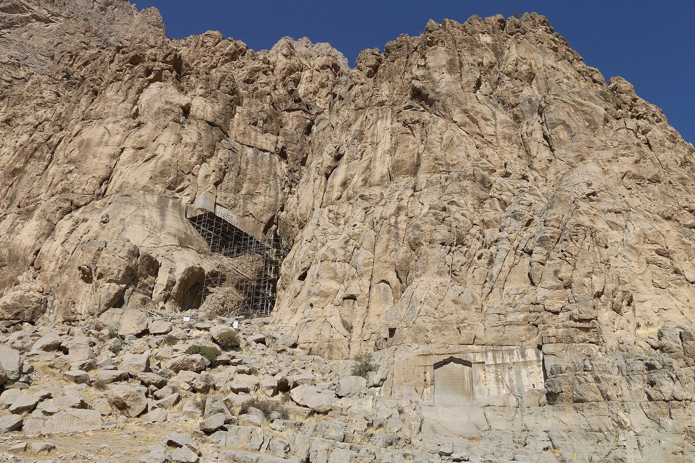The limestone cliff of Behistun rising above the plain in Kermanshah province, Iran, with the carved panel high on the rock face