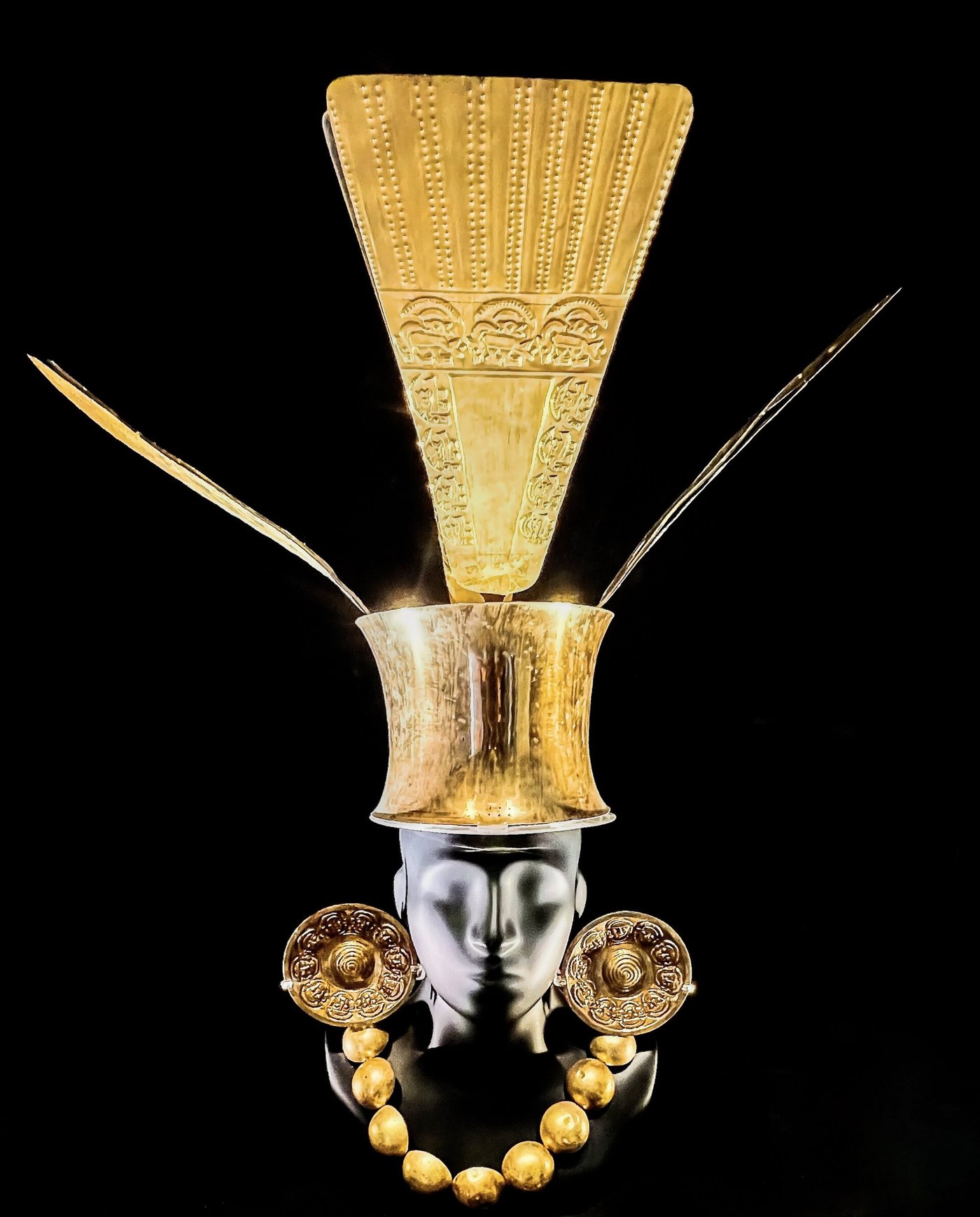 Chimu gold funerary ornaments, including a headdress and face pieces, displayed against a black background