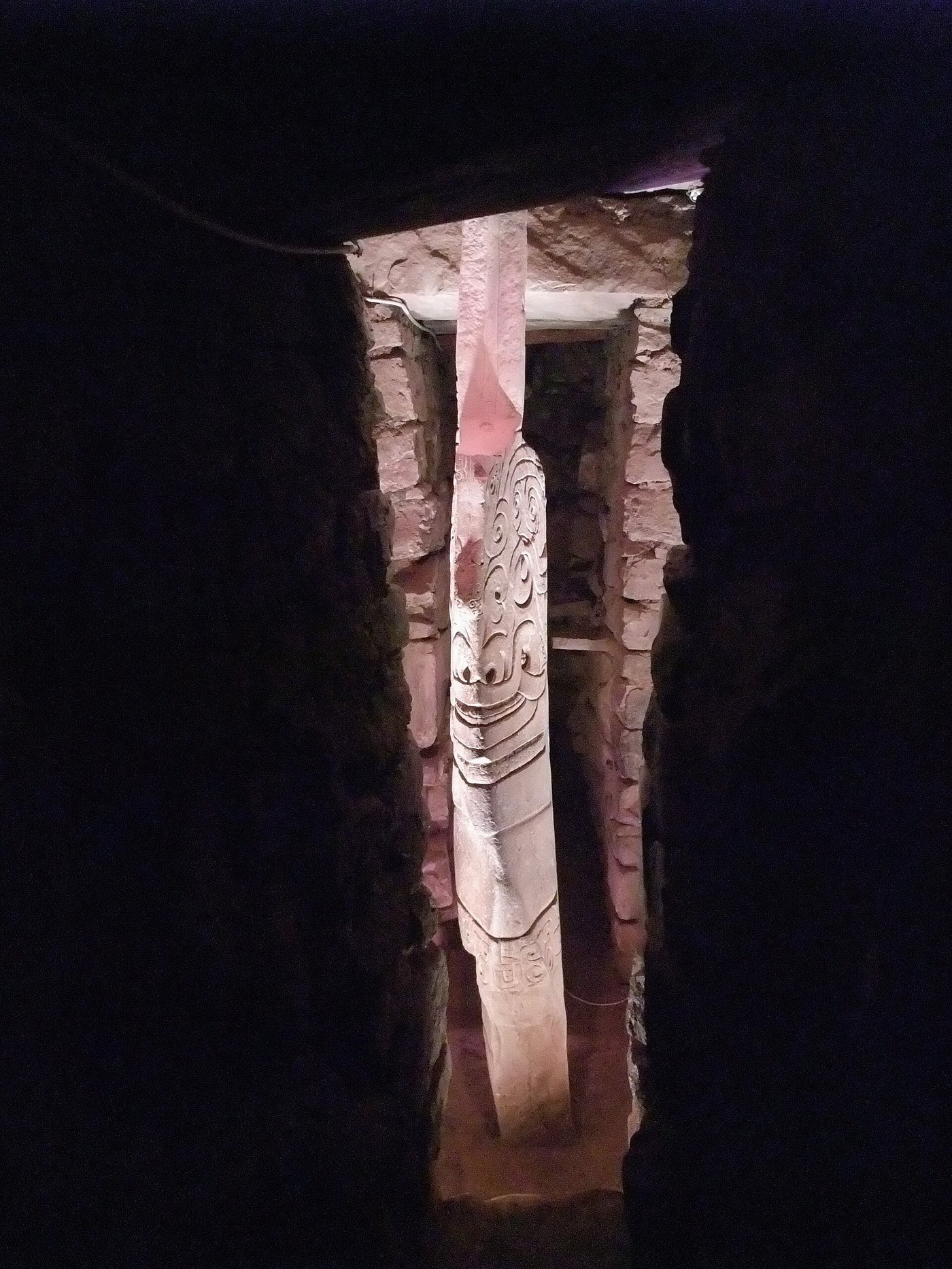 The Lanzón, a tall carved granite monolith in a narrow gallery at Chavín, depicting a fanged deity with one arm raised
