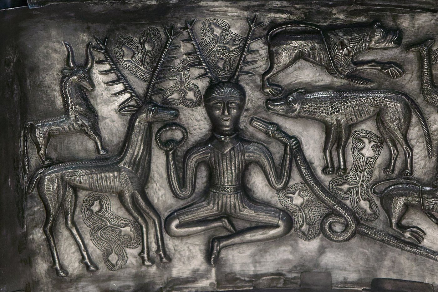 The antlered figure on an inner plate of the Gundestrup cauldron, sitting cross-legged holding a torc in one hand and a ram-horned serpent in the other, surrounded by a stag, a hound and other animals