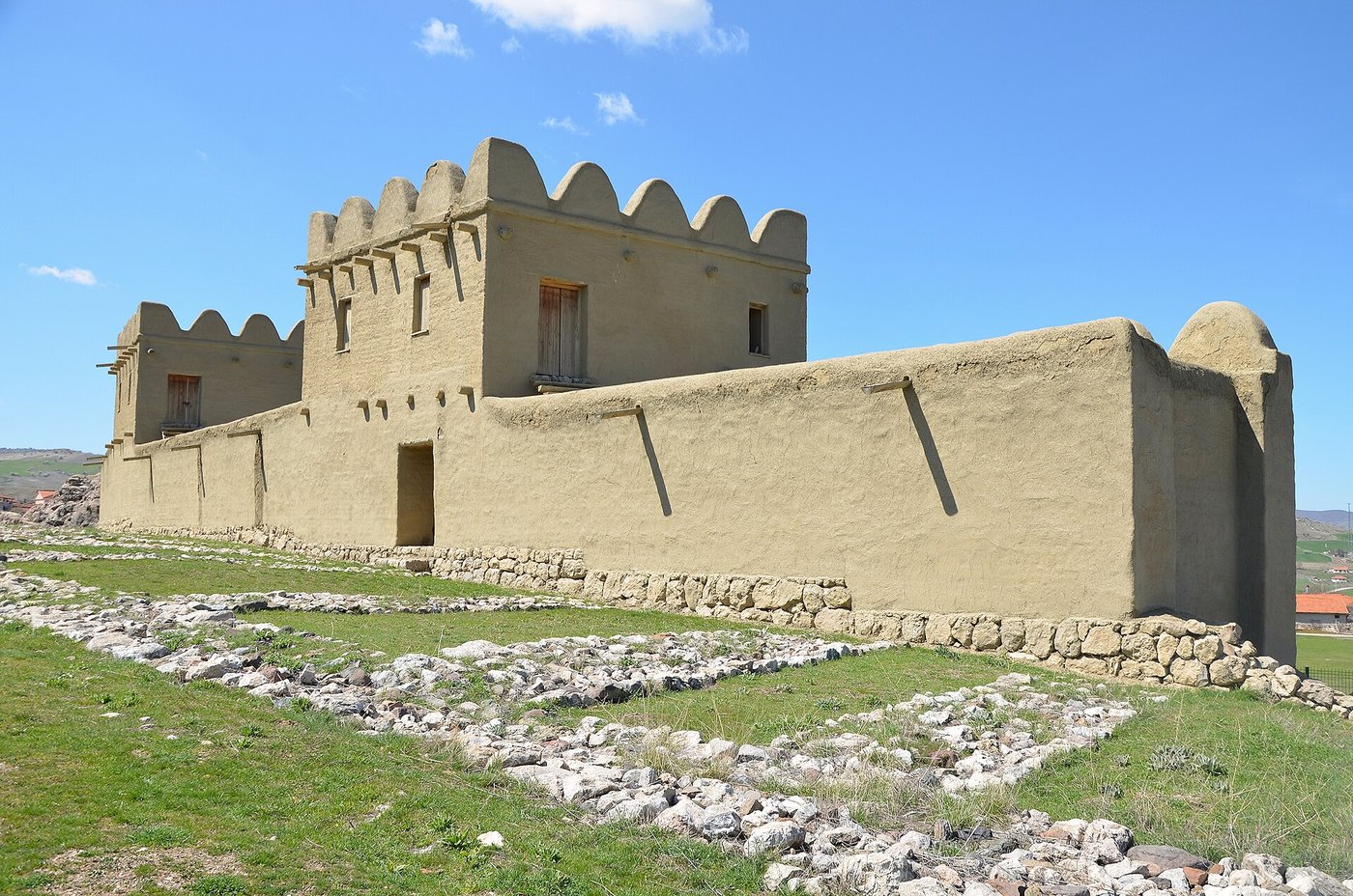 A reconstructed section of the mud-brick city wall of Hattusa, tall and pale against a grassy slope