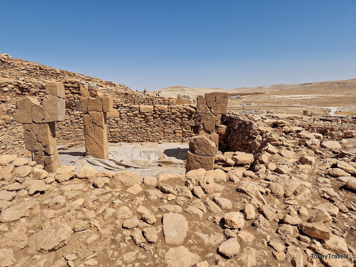 A row of tall T-shaped stone pillars inside an enclosure at Karahan Tepe