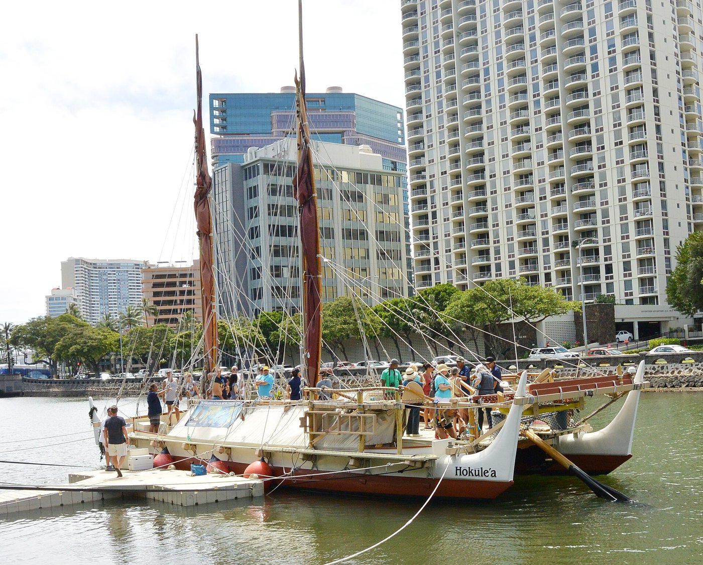 A modern double-hulled Polynesian voyaging canoe with twin sails, on the water