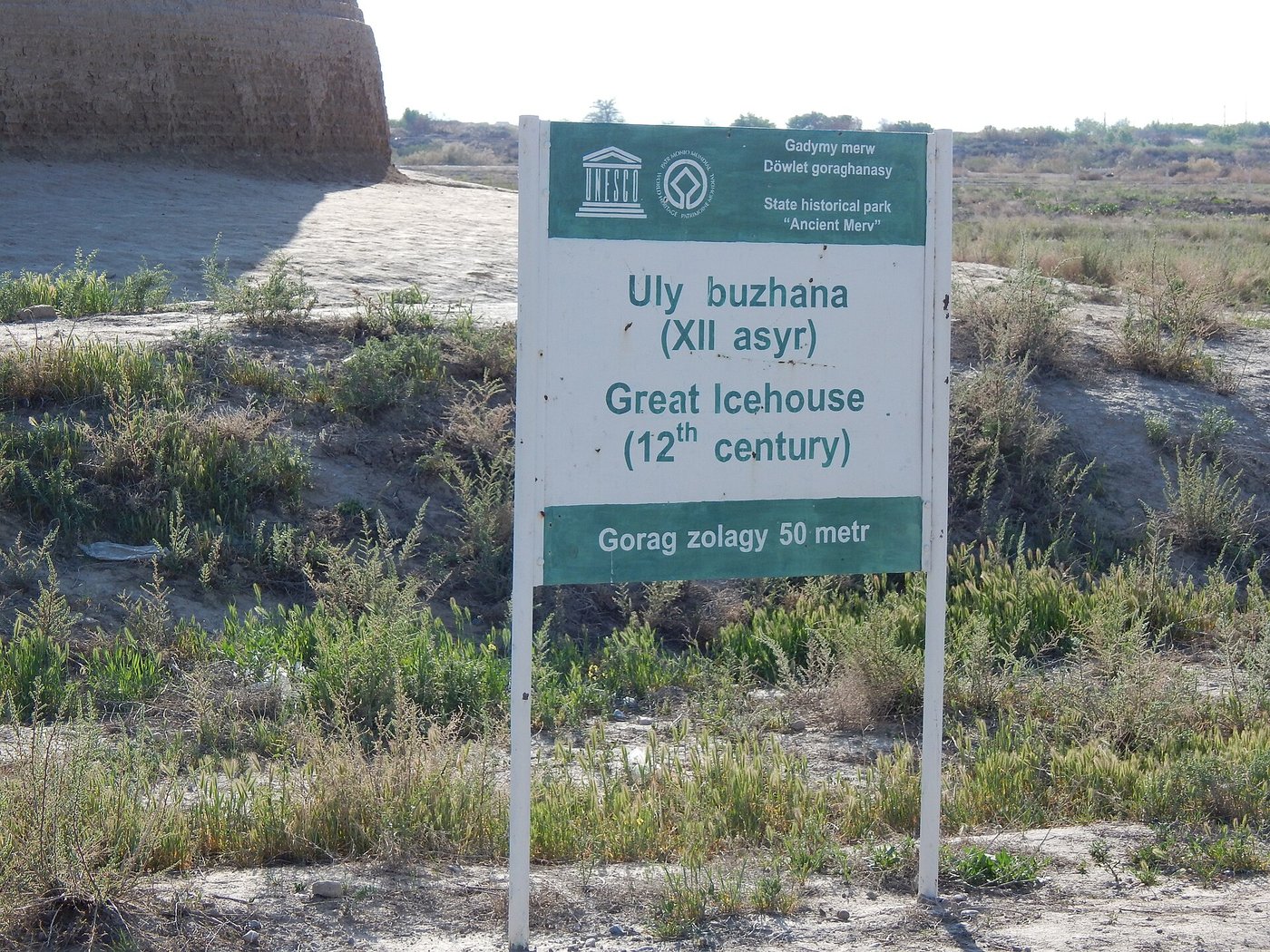 A tall conical mud-brick ice house standing alone on the flat plain of Merv, its curved walls weathered but intact