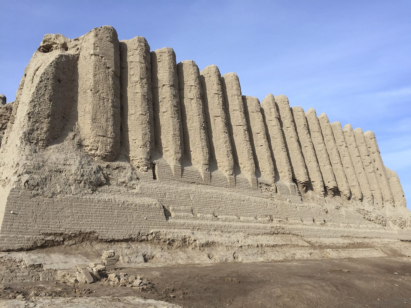 The Greater Kyz Kala at Merv, a massive earthen building with distinctive corrugated, rippling walls like organ pipes, standing on the desert plain
