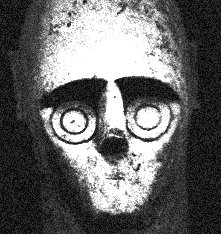 Close-up of a Mont'e Prama giant's head in pale sandstone, with a flat T-shaped brow and nose and two concentric incised circles for each eye