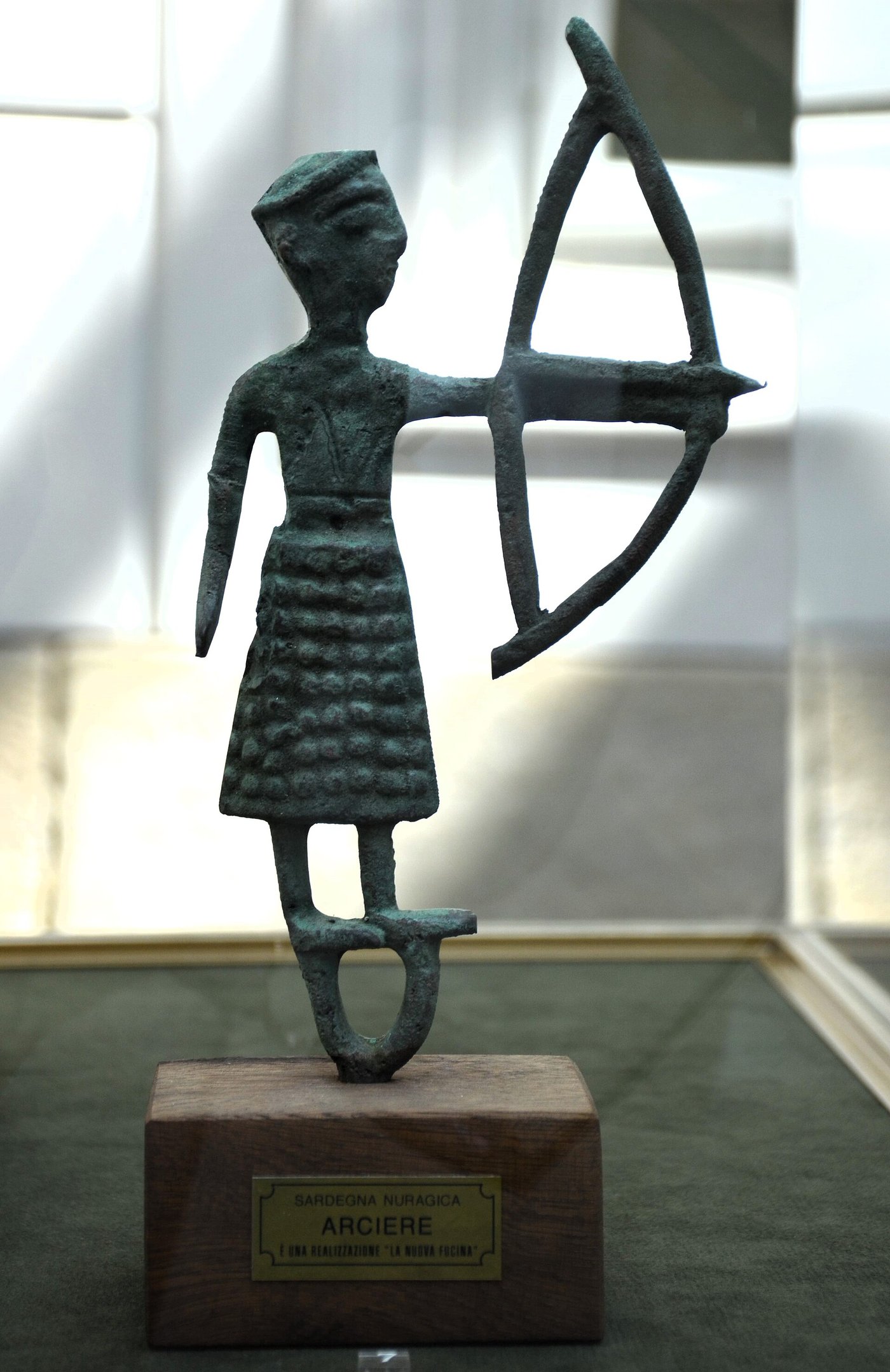 A small Nuragic bronze figurine of an archer, early Iron Age, with a bow held across the body and a horned helmet, from Sardinia