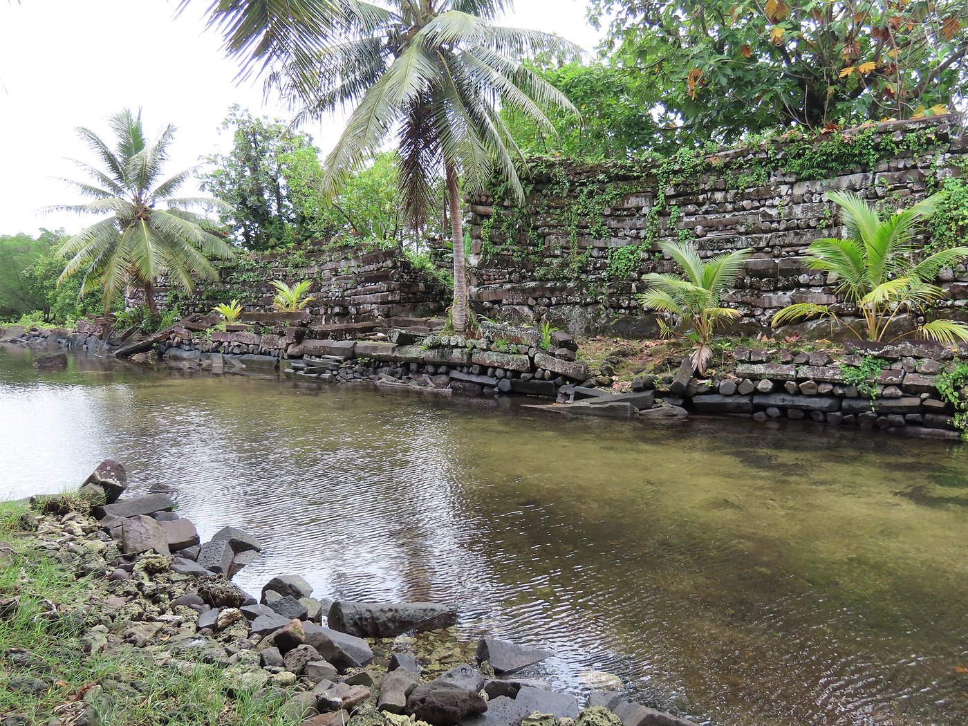 A tidal canal running between stone-walled islets at Nan Madol under a bright sky