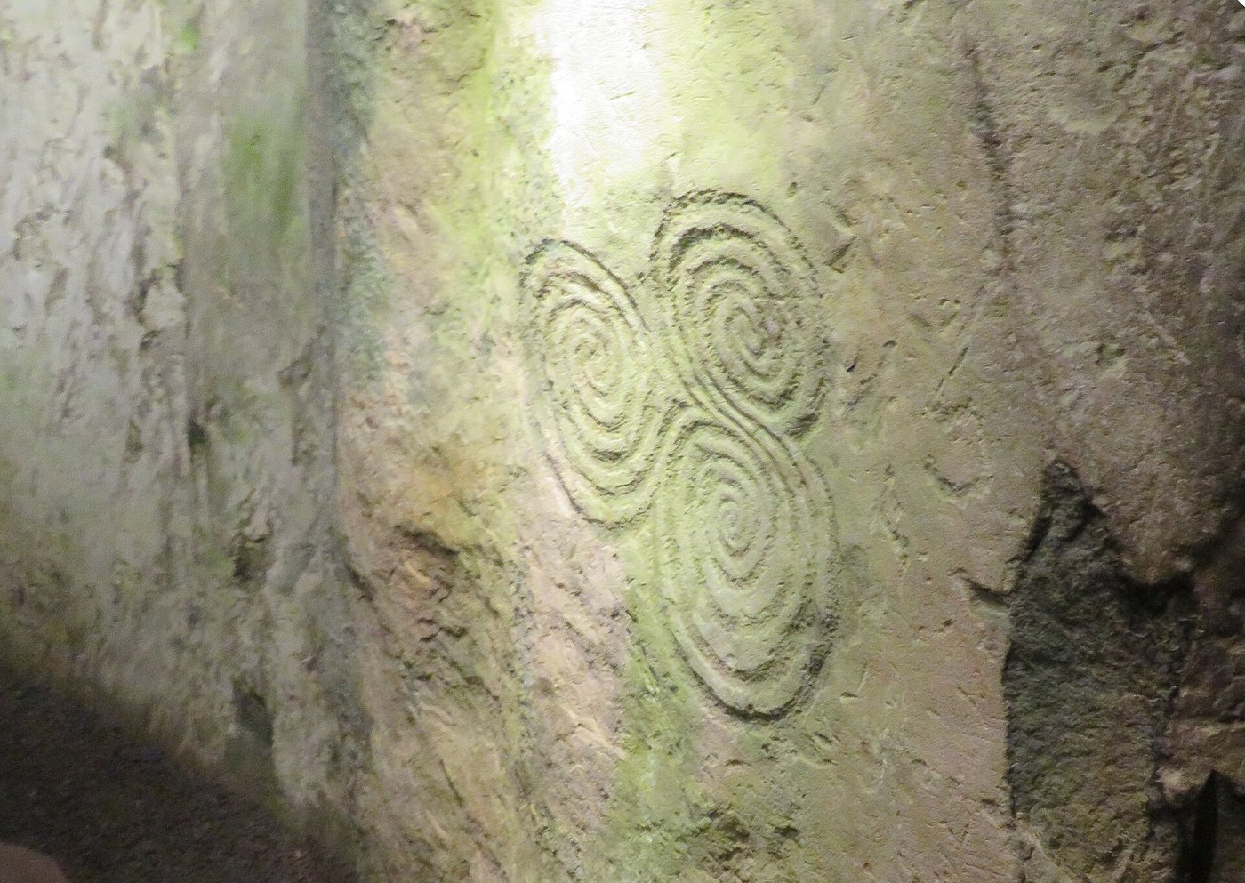 The famous triple spiral carved on an orthostat deep inside the Newgrange chamber, lit by a torch beam