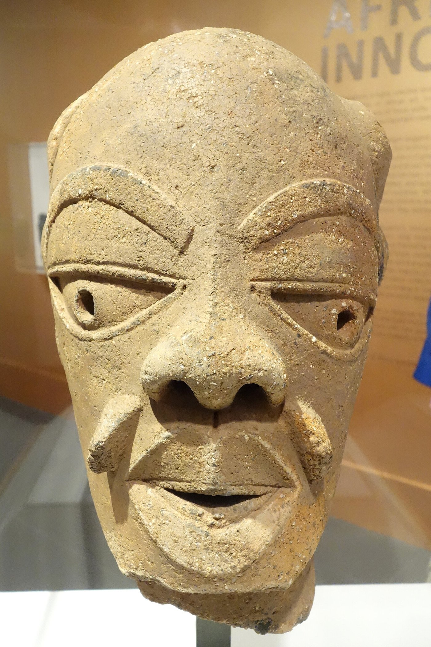 Terracotta Nok head with large triangular eyes, arched brows and an elaborate coiled hairstyle
