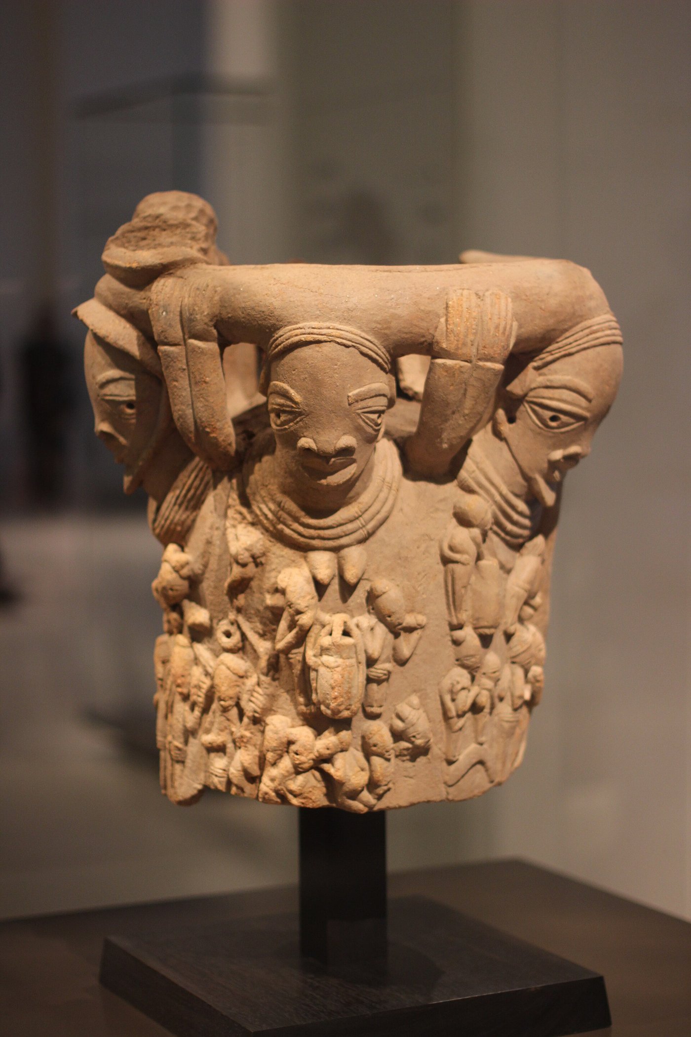 Near life-size hollow Nok terracotta figure of a seated person adorned with beads, on display in a museum