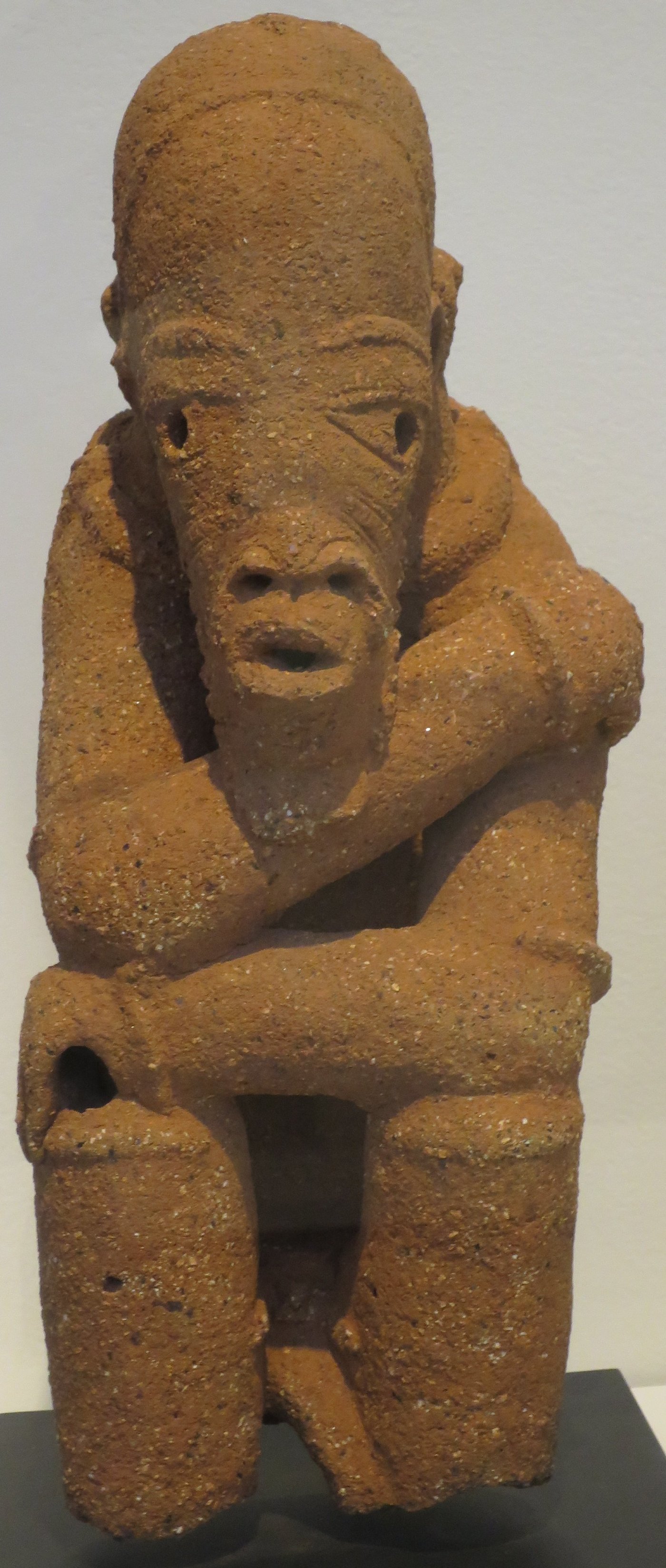 Kneeling Nok terracotta figure with beaded ornaments, hands resting on the thighs