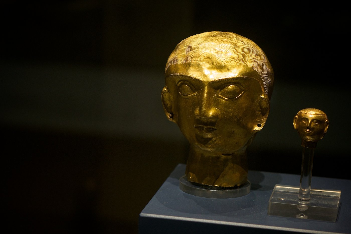 A group of small gold heads and ornaments from the treasure displayed together