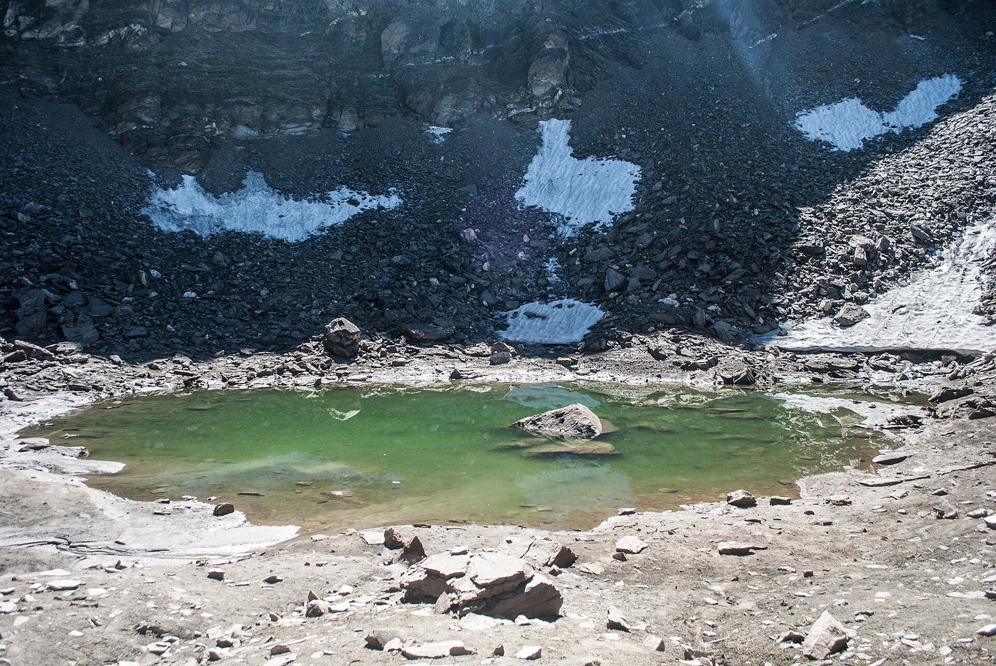 The small glacial lake at Roopkund in the Himalayas, ringed by loose scree and snow