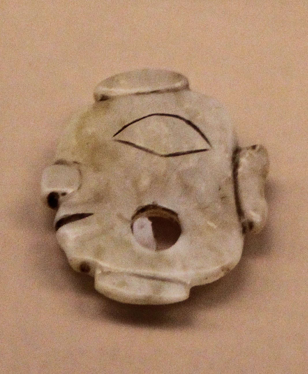 Carved jade human face from the Shimao site, pale stone with stylised eyes and features