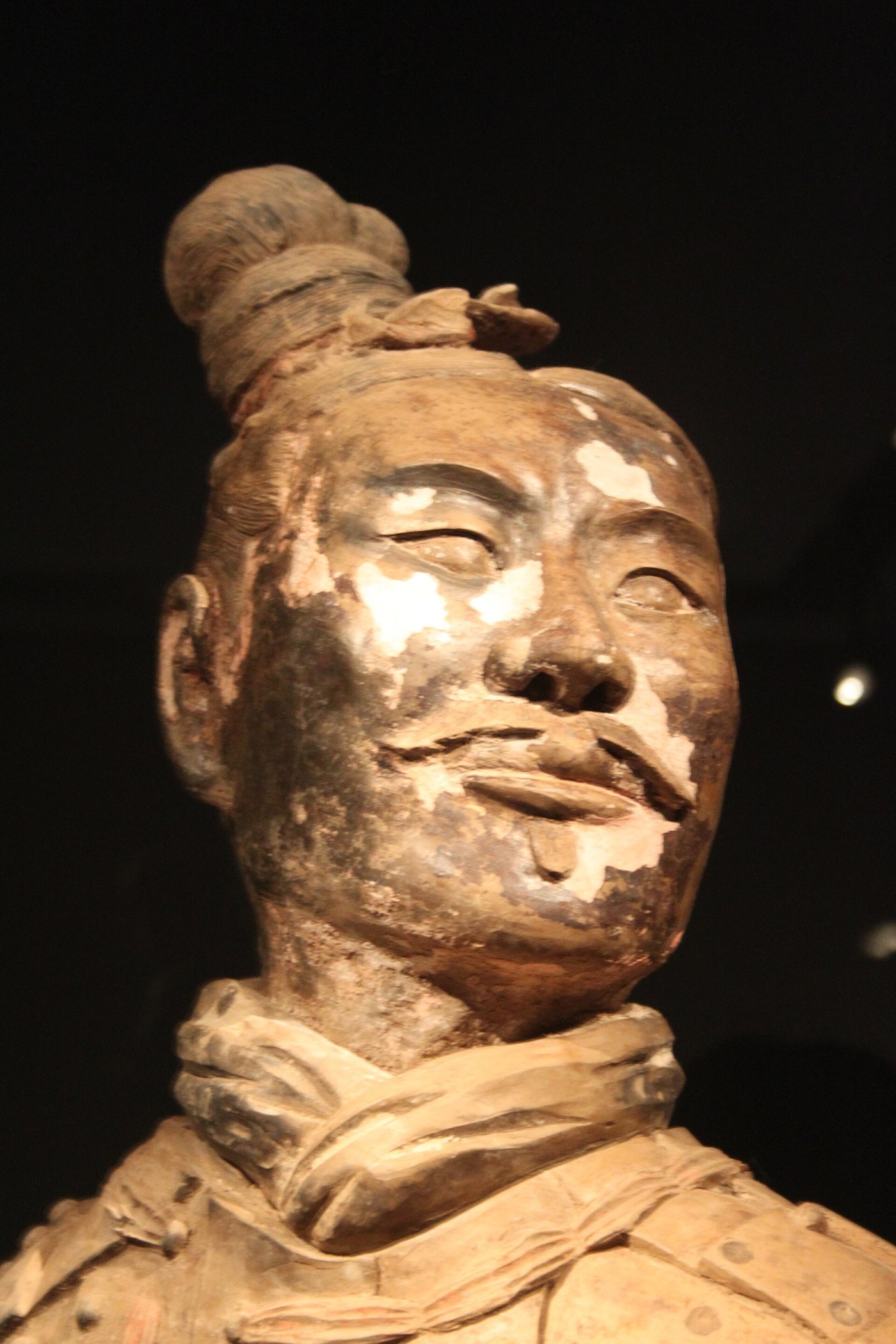The head of a terracotta figure with patches of the original pale pigment still clinging to the face and features