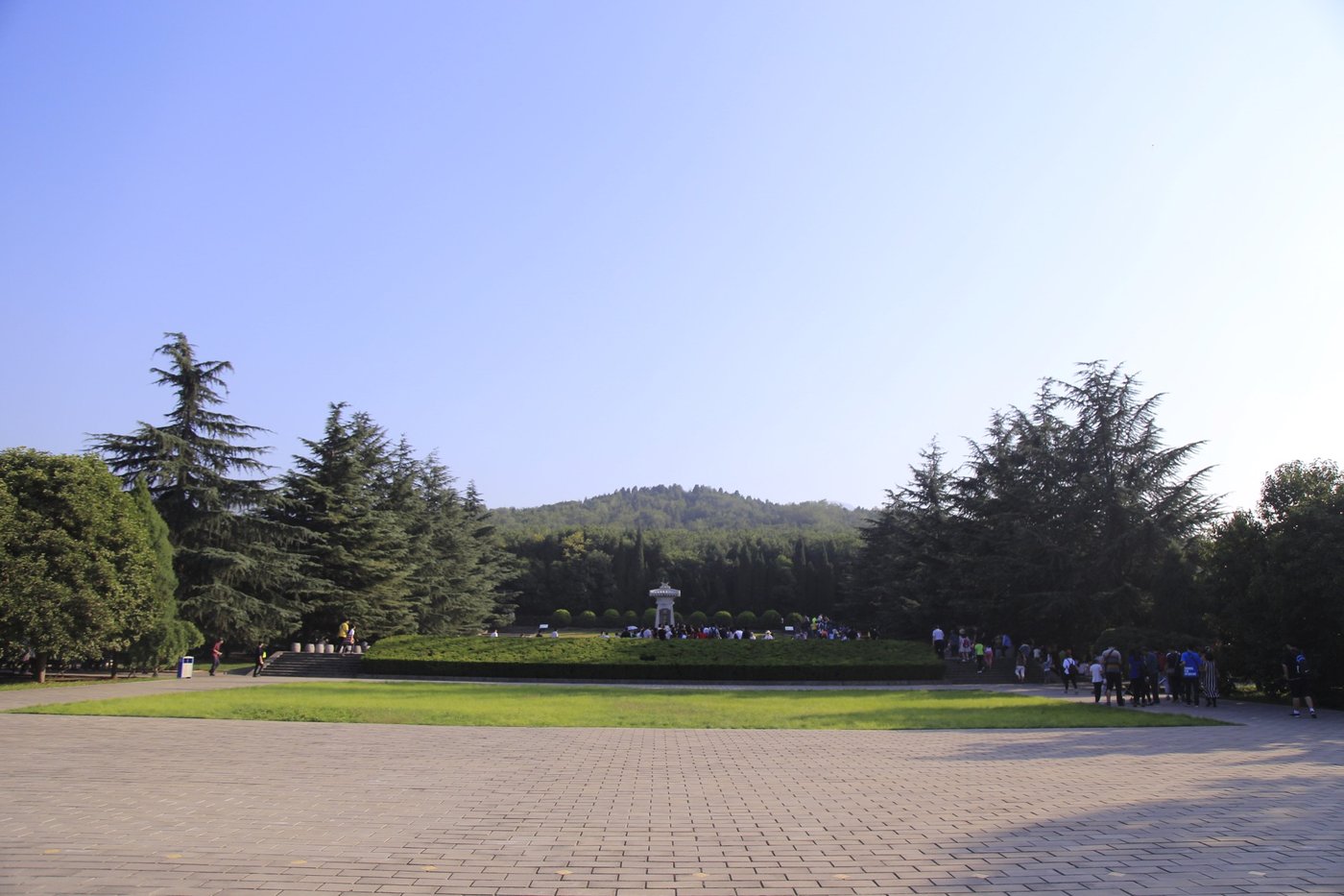 The tree-covered burial mound of Qin Shi Huang rising behind a visitors' plaza and low hedges