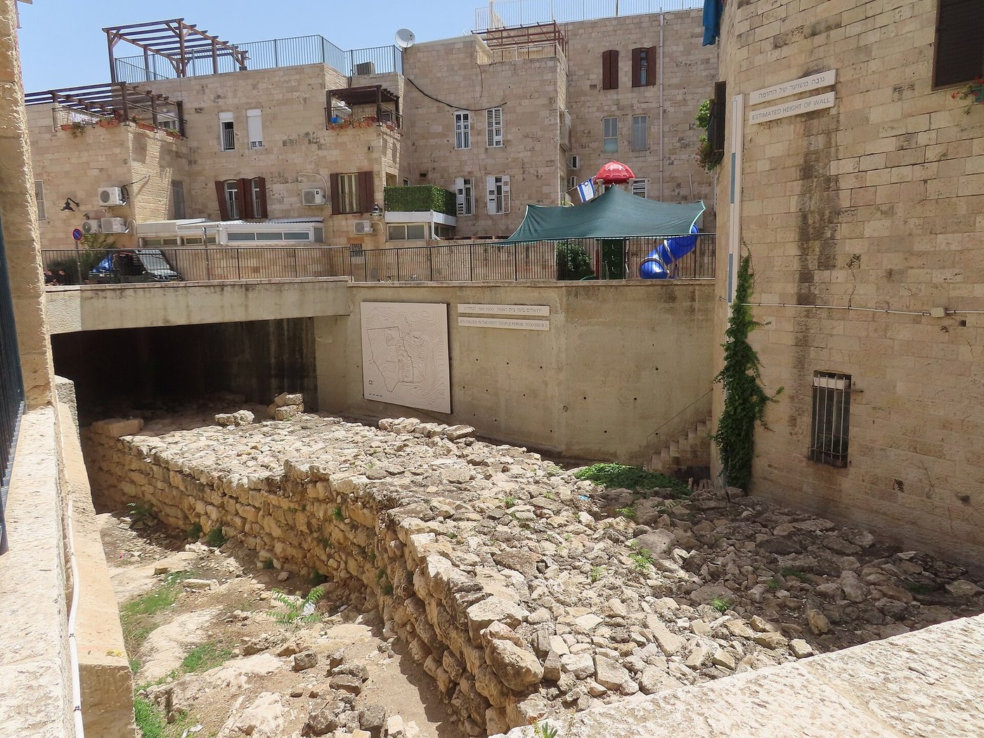A massive exposed stretch of ancient stone wall, several metres thick, preserved below street level in Jerusalem's Jewish Quarter