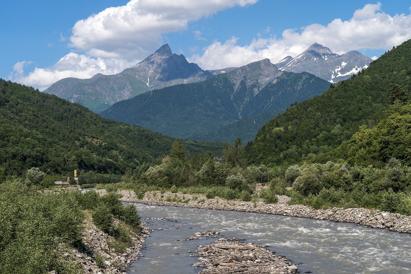 A fast, clear mountain river running over pale gravel between wooded banks in the Georgian Caucasus