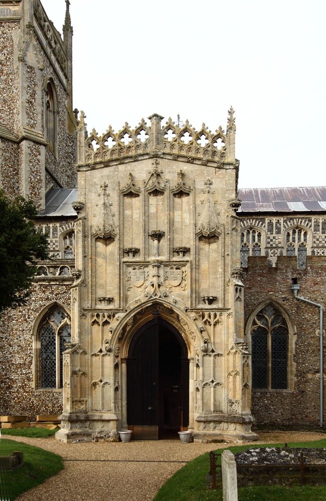 The ornate medieval stone porch of St Mary’s Church, Woolpit, with carved tracery and Gothic arches
