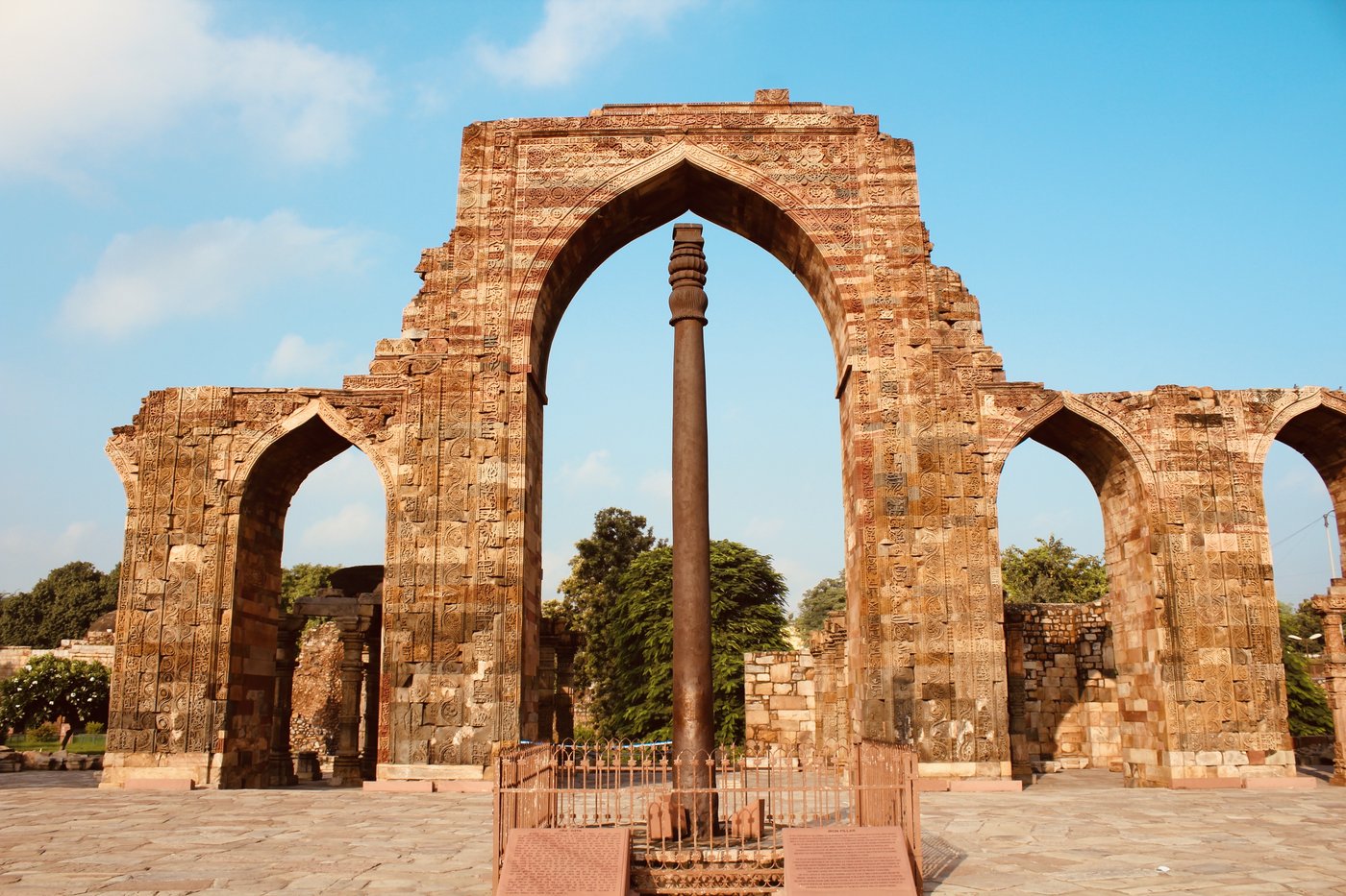 The iron pillar standing in the paved courtyard of the Qutb complex, ringed by a low railing