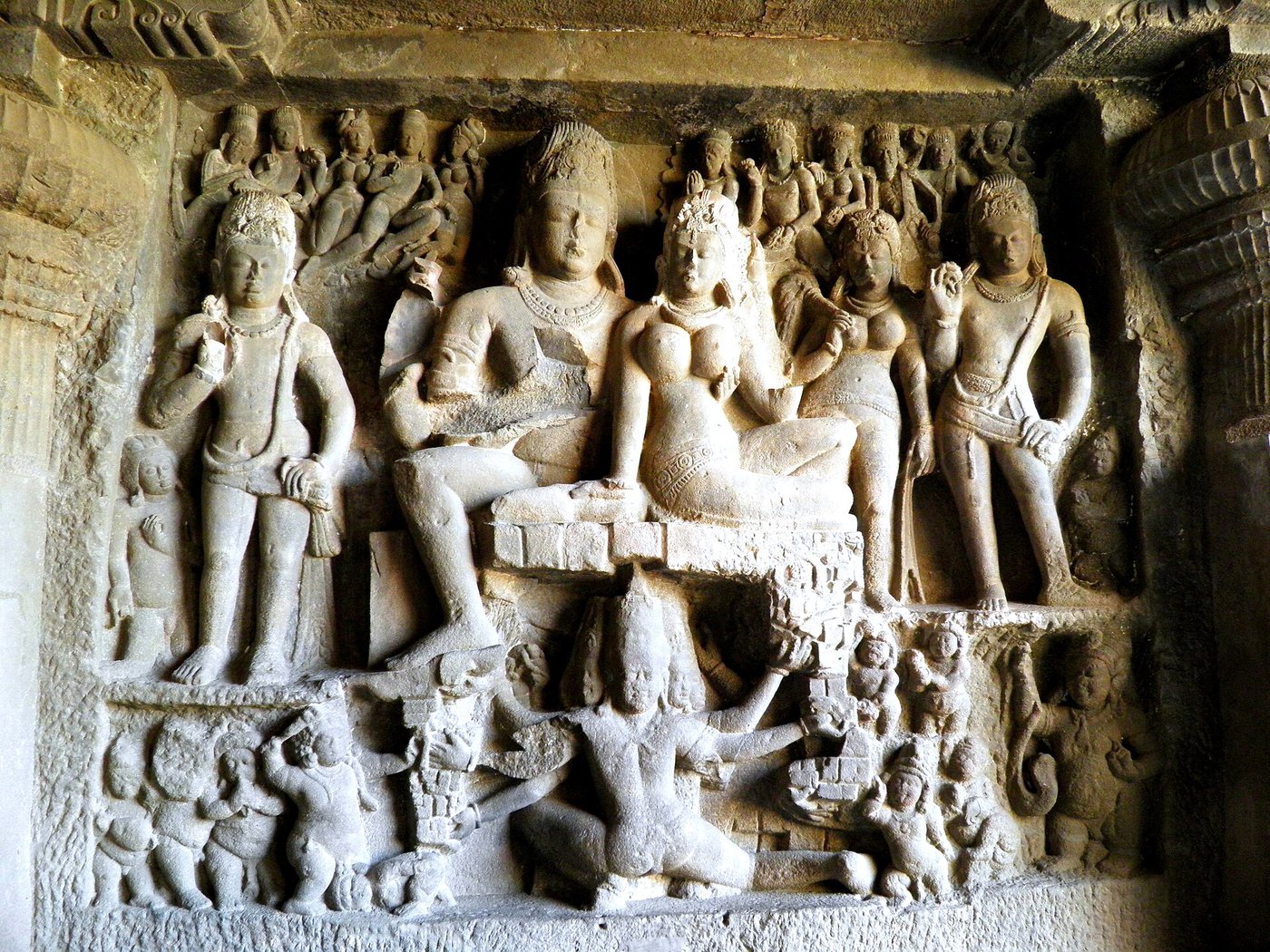 Carved relief panel at the Kailasa Temple showing the demon Ravana beneath Mount Kailasa with Shiva seated at the summit