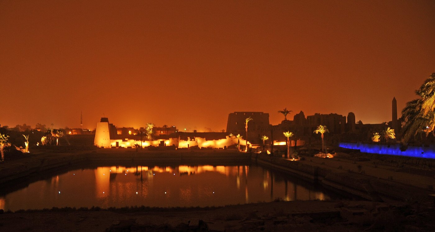 The great Sacred Lake at Karnak, a large rectangular stone-edged basin of green water beside the temple ruins