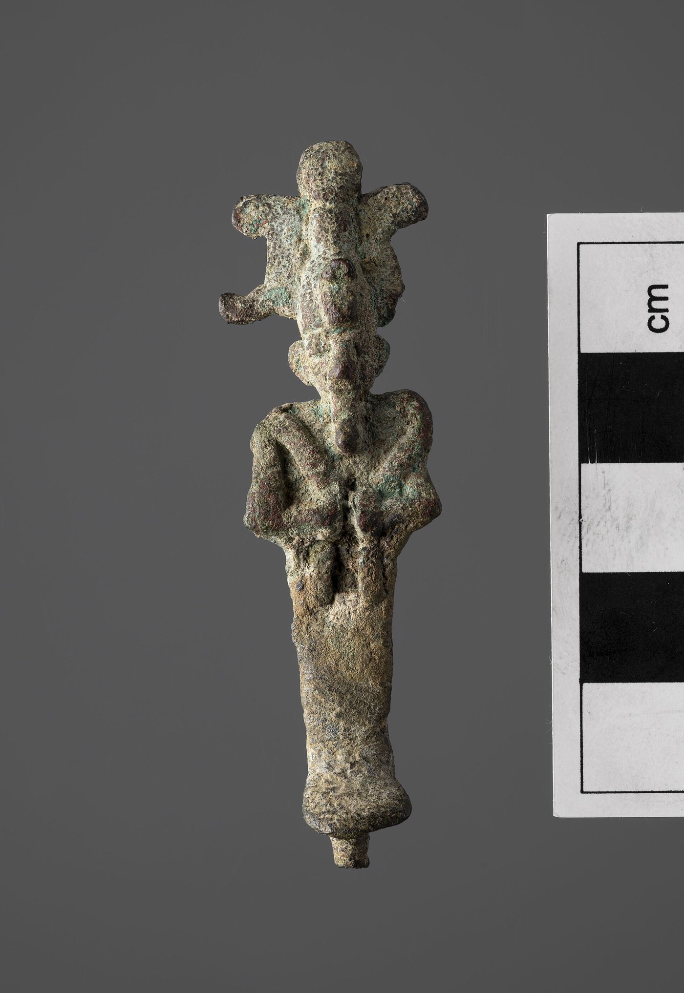 A small bronze statuette of the god Osiris, mummiform, holding crook and flail and wearing the tall atef crown