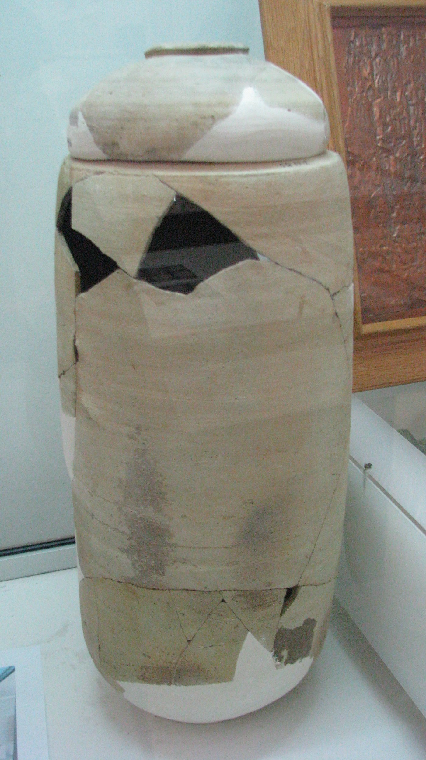 A restored storage jar of the type used to hold Dead Sea Scrolls, beside a facsimile of the Copper Scroll