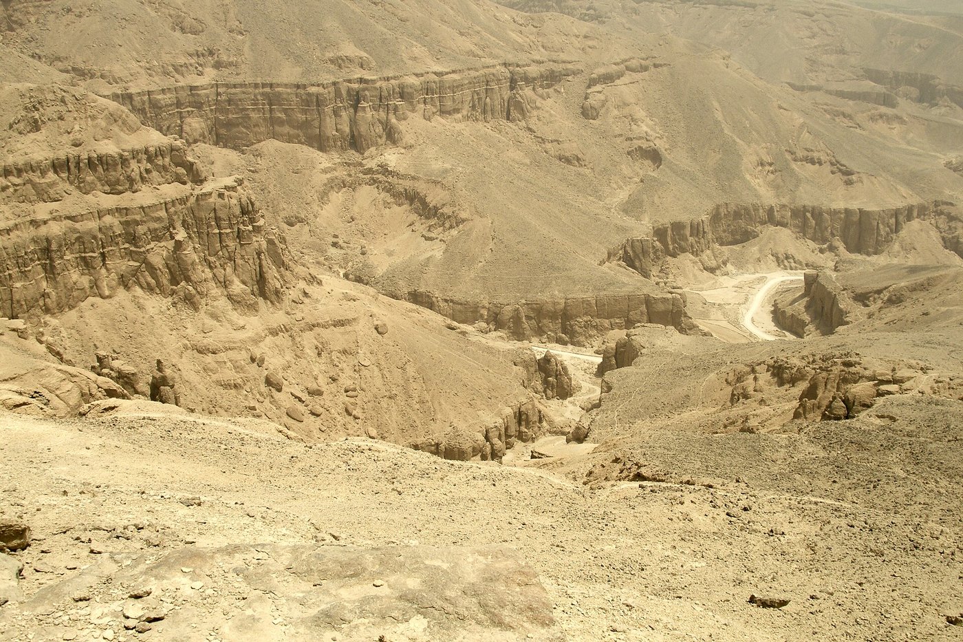 The bare limestone hills of the Valley of the Kings under a clear sky, honeycombed with tomb entrances