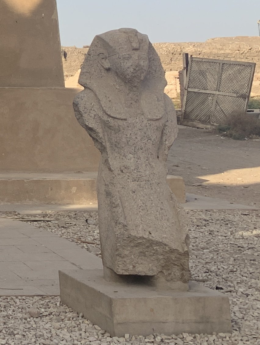 A stone statue of the pharaoh Thutmose III standing in the open-air museum at Karnak