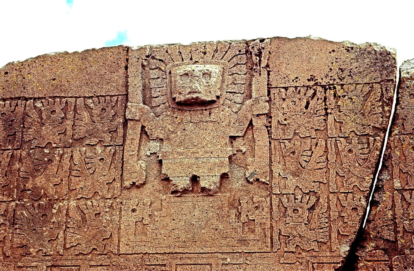 Carved detail of the central staff-bearing figure on the Gate of the Sun, with rays around the head and a staff in each hand
