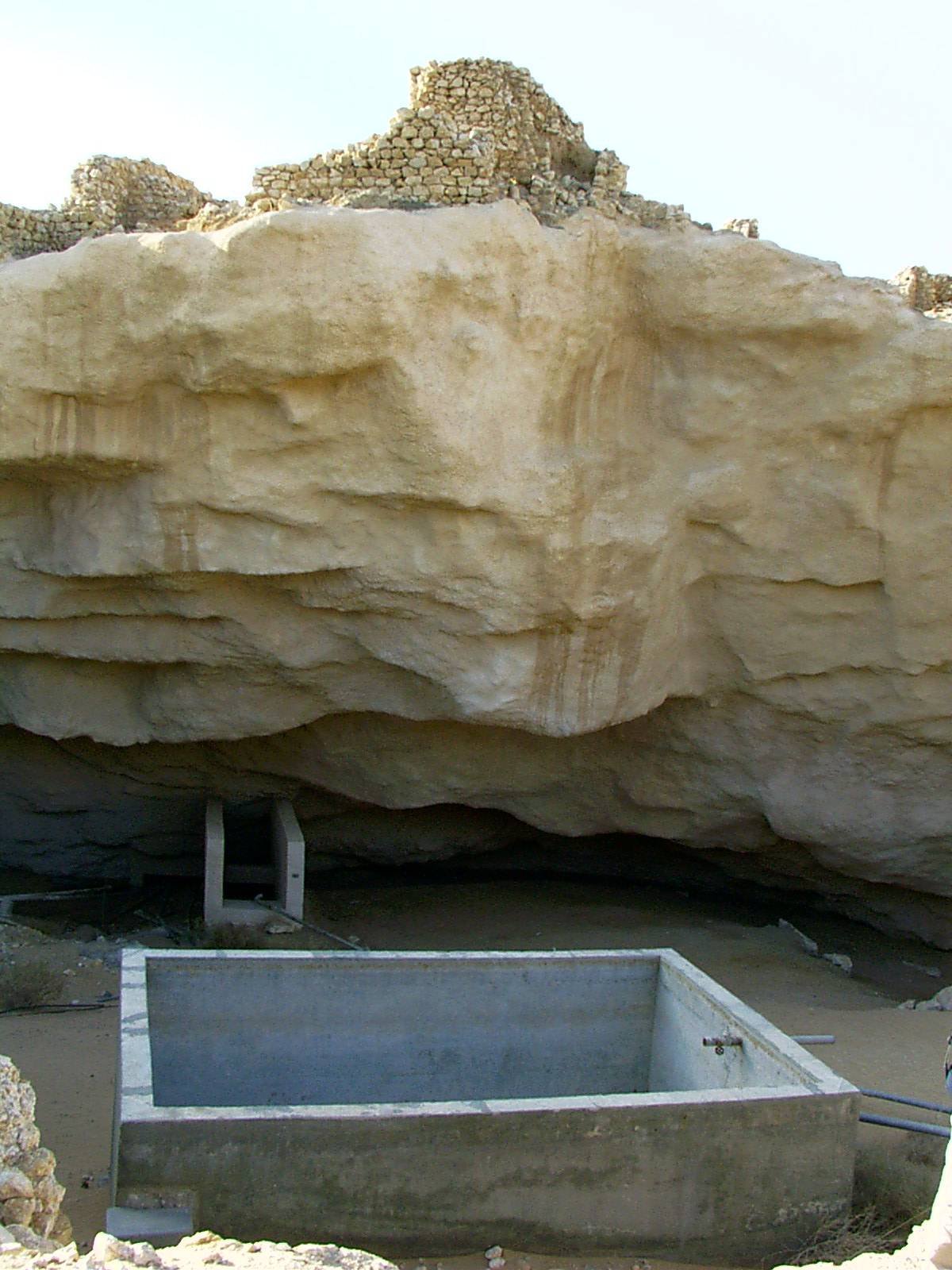 The collapsed limestone sinkhole at the ancient site of Shisr, or Ubar, in Oman, with ruined walls at its edge