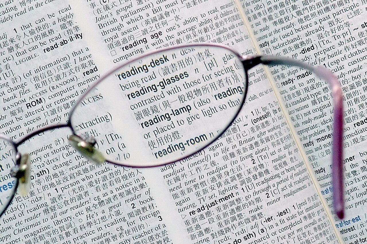 A pair of reading glasses resting on a page of small print
