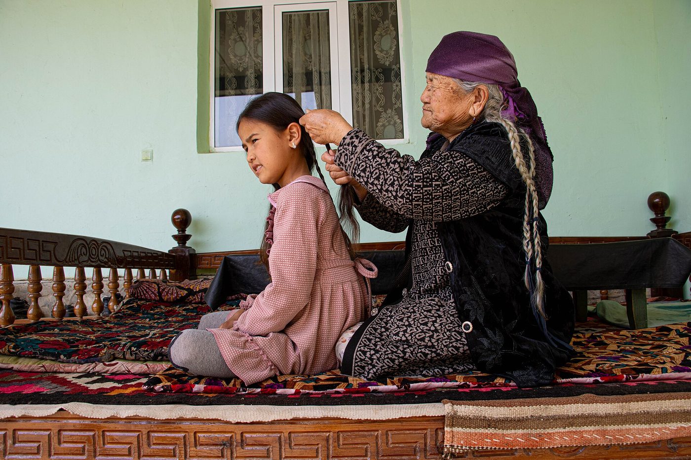 A grandmother braiding her granddaughter's hair